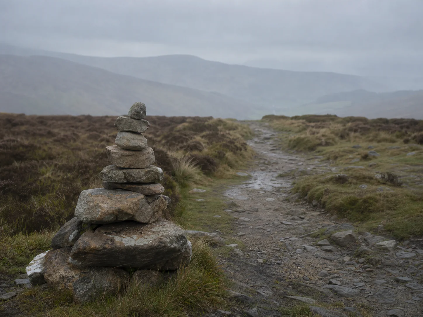 A stone cairn marking a misty upland trail
